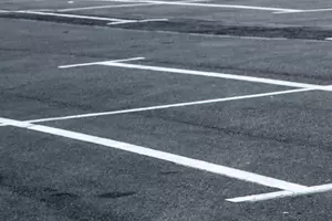 Empty parking lot with white painted lines marking parking spaces on an asphalt surface.